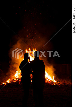 Silhouette of a couple in front of a giant bonfire 68417266