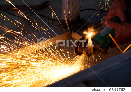 Unsafe Worker Cutting Metal Construction with no Protection Uniform with Electric Wheel Grinding Machine in the Construction Site. Unsafe Worker Cutting Metal Construction with no Protection Uniform with Electric Wheel Grinding Machine in the Construction Site. 68417624