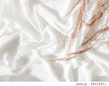 Top view on dried grass. Flat lay still life concept. Decorative autumn plants on crumpled white fabric. Cozy home background with copy space. Handmade natural decorations. Sunlight and shadow. 68419931