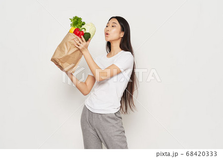 Slender woman in sportswear holds in her hand a packet with vegetables calorie Slender woman in sportswear holds in her hand a packet with vegetables calorie 68420333