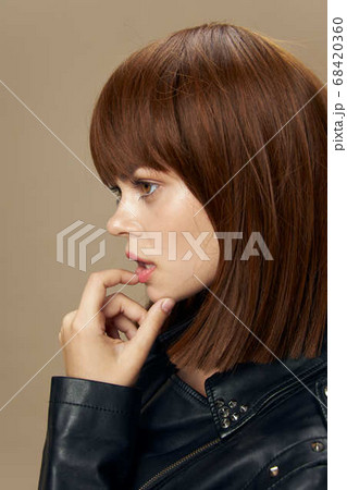 Young beautiful woman posing on a beige background in the studio in a black leather jacket 68420360