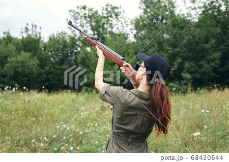 Military woman holding gun up sight hunting back view fresh air green  68420644