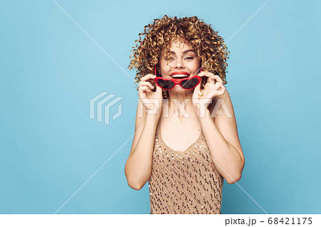 Enthusiastic blonde party on a blue background, red sunglasses Enthusiastic blonde party on a blue background, red sunglasses 68421175