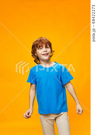 A red-haired boy in a blue T-shirt on a yellow background smiles A red-haired boy in a blue T-shirt on a yellow background smiles 68422273
