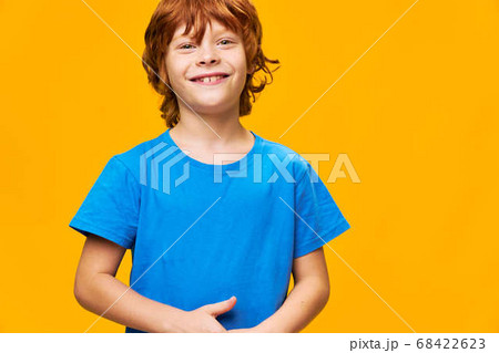 red-haired happy boy on yellow background in blue t-shirt  68422623