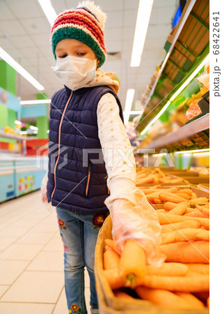 kid girl in medical mask, gloves buys carrot 68422641
