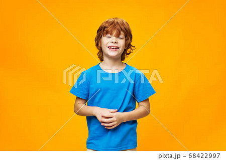 red haired handsome boy in a blue t-shirt on a yellow background smiling 68422997
