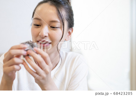 自宅できんつばを食べる若い女性 68423205