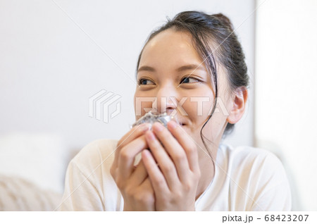 自宅できんつばを食べる若い女性 68423207