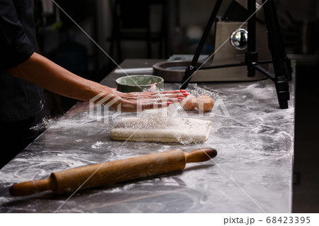 The chef prepares pastries in a professional kitchen. Dark background. The chef prepares pastries in a professional kitchen. Dark background. 68423395