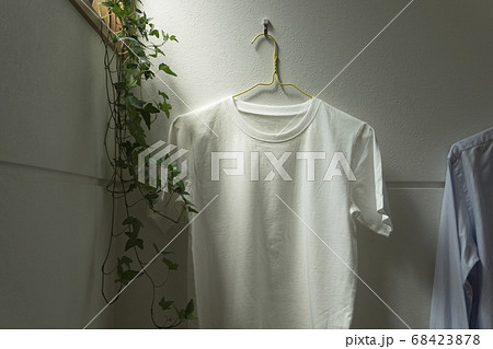 部屋にかけられた一枚の白いtシャツ。部屋、リビング、部屋干し、洗濯など 部屋にかけられた一枚の白いtシャツ。部屋、リビング、部屋干し、洗濯など 68423878