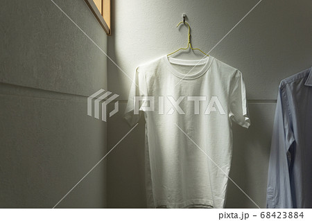 部屋にかけられた一枚の白いtシャツ。部屋、リビング、部屋干し、洗濯など 部屋にかけられた一枚の白いtシャツ。部屋、リビング、部屋干し、洗濯など 68423884