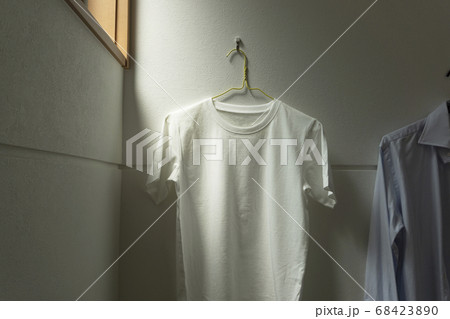 部屋にかけられた一枚の白いtシャツ。部屋、リビング、部屋干し、洗濯など 部屋にかけられた一枚の白いtシャツ。部屋、リビング、部屋干し、洗濯など 68423890