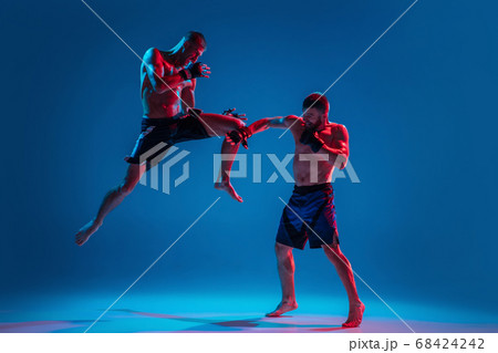 MMA. Two professional fighters punching or boxing isolated on blue studio background in neon MMA. Two professional fighters punching or boxing isolated on blue studio background in neon 68424242