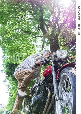 バイクライフ キックスターターでバイクのエンジンを始動するシニアライダーの写真素材