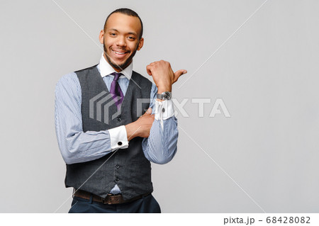 Happy african-american businessman showing his thumb up with smile over grey background Happy african-american businessman showing his thumb up with smile over grey background 68428082