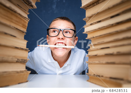 Smart looking boy holding pencil in his mouth, looking away and thinking. Researching, studying and solving problem with concentration Smart looking boy holding pencil in his mouth, looking away and thinking. Researching, studying and solving problem with concentration 68428531