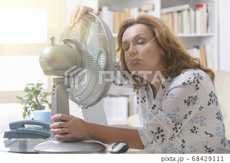 Woman suffers from heat in the office or at home Woman suffers from heat in the office or at home 68429111
