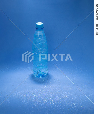 Blue plastic water bottle on a blue background with water drops 68429530