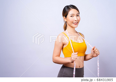 Asian sporty woman measuring her waist by measure tape isolated on white backgroun Asian sporty woman measuring her waist by measure tape isolated on white backgroun 68431905