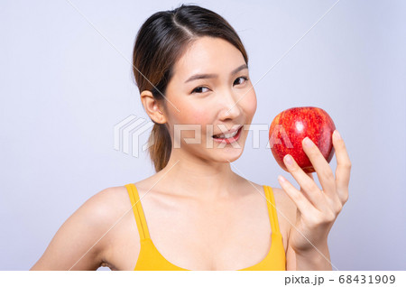 A sporty Asian woman in sportswear holding an apple isolated on white background 68431909