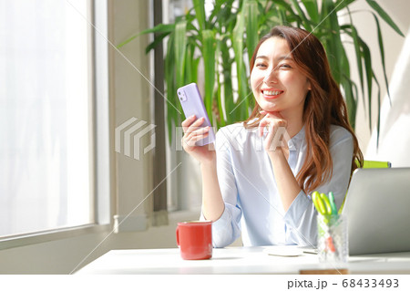 スマホを持ち優しく微笑む女性 68433493
