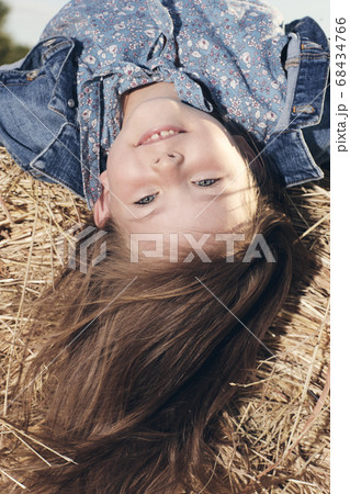 Portrait of a little girl upside down on a haystack Portrait of a little girl upside down on a haystack 68434766
