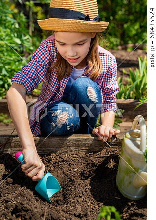 little teen girl in hat planting seedlings 68435524
