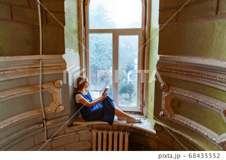 woman sits of window in old house and reads book 68435552