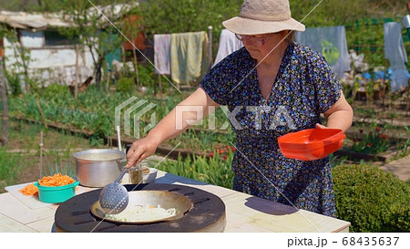 woman fry onions in tandir in garden. 68435637
