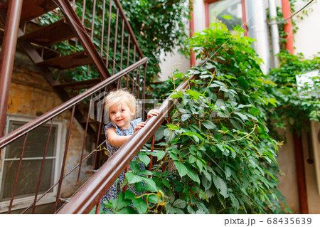 little girl stand in old yard with leafy  stair. 68435639