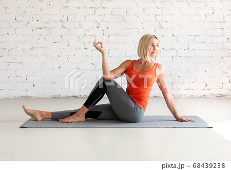 Attractive caucasian woman practice hatha yoga indoor in loft white studio. Seated side twist pose, selective focus. 68439238