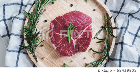 Raw meat, beef steak, on wooden board with rosemary	 68439805