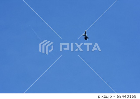 急上昇するアメリカ空軍のF-16戦闘機とはるか上空を飛ぶ民間機の飛行機雲 68440169