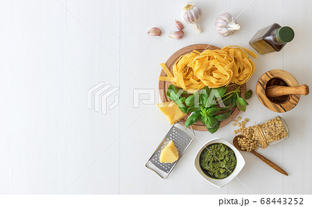 Ingredients to produce basil pesto, olive oil, pine nuts, basil, parmesan cheese with white background Ingredients to produce basil pesto, olive oil, pine nuts, basil, parmesan cheese with white background 68443252