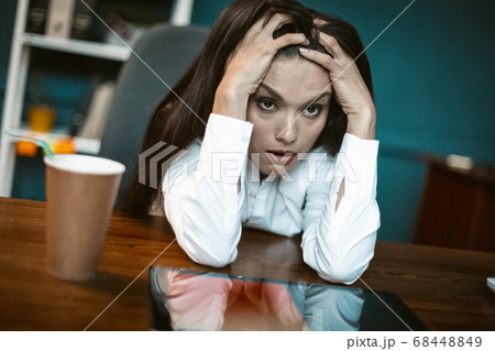 Stressed business woman feels emotional stress. Bored or crazy woman falling into stupor with coffee cup at workplace. Crisis concept. Tinted image Stressed business woman feels emotional stress. Bored or crazy woman falling into stupor with coffee cup at workplace. Crisis concept. Tinted image 68448849