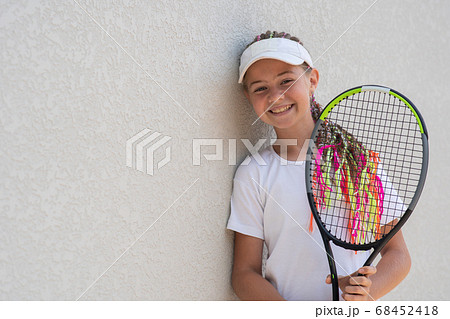 Beginner smiling girl tennis player with a tennis racket in her hands. 68452418