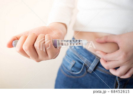 Close up of female diabetes patient making subcutaneous insulin injection into her abdomen with insulin pen syringe for at home. Diabetes, health care and medical concept. Diabetes World Day. 68452615