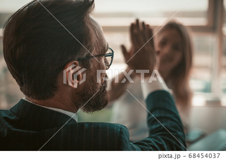 Positive project managers celebrate successful deal. Enthusiastic business people giving five each other in sign of good job and hands solidarity. American spirit concept. Close up shot. Tinted image 68454037