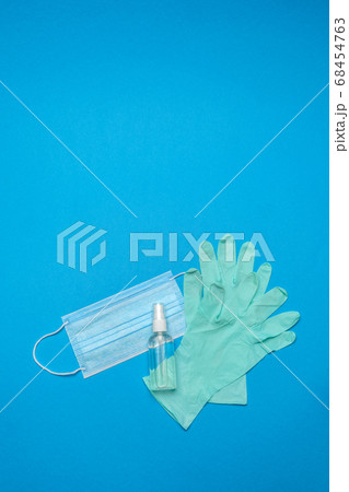 Disposable blue medical face mask, rubber latex gloves and alcohol hand sanitizer antiseptic on blue background 68454763