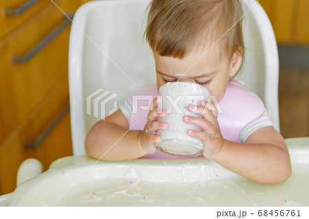 portrait of a child who drinks yogurt from a glass. smeared face with food 68456761