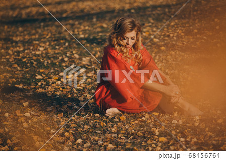 beautiful girl in a red dress in the autumn forest. nature walk. getting energy from the sun, trees. fairitale scene of a woman laying in the forest 68456764