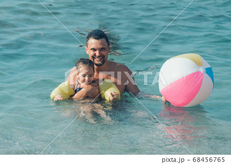 A young father and daughter swim in the sea. swimming training. ball game 68456765