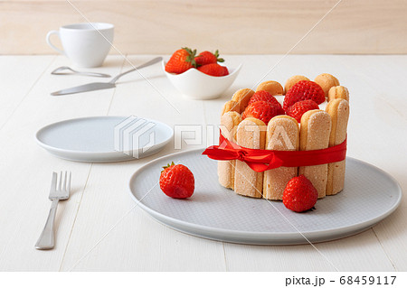 Charlotte, French strawberry dessert, tied up with a scarlet ribbon, cup of coffee, white background Charlotte, French strawberry dessert, tied up with a scarlet ribbon, cup of coffee, white background 68459117