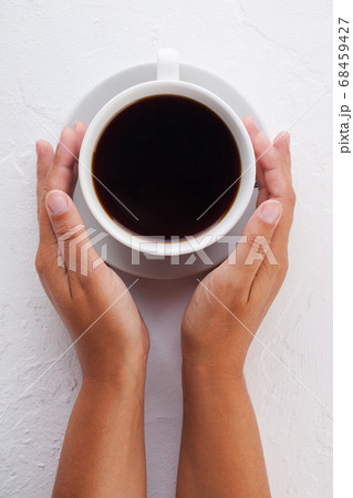 women's hands hold a white coffee mug on a white 68459427