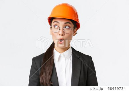 Close-up of impressed asian female chief architect, industrial engineer in safety helmet and business suit, looking left surprised and amazed, standing white background at factory Close-up of impressed asian female chief architect, industrial engineer in safety helmet and business suit, looking left surprised and amazed, standing white background at factory 68459724