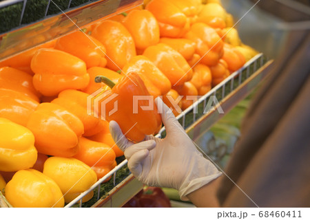 young women in protective gloves holding capsicum at retail store  68460411
