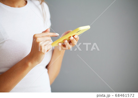 Close up front view young woman holding smartphone, typing message, chatting with friends in social networks. Close up front view young woman holding smartphone, typing message, chatting with friends in social networks. 68461572