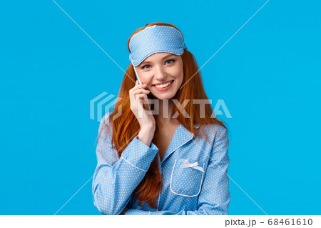 No you hang first. Lovely and beautiful redhead girlfriend talking phone till midnight, wearing sleep mask and nightwear, holding smartphone, calling boyfriend smiling silly, blue background 68461610