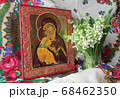 Traditional orthodox icon of the Mother of God. Icon Vladimirskaya. Handwritten icon of the Virgin Mary with Jesus Christ on the background of Ukrainian rushnyks and lilies of the valley. 68462350